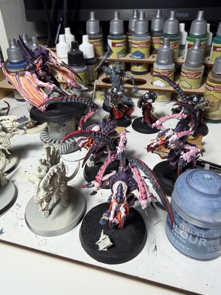 Prime tyranide ailé et Bondisseurs peints sur l'établi, entourés de pots de Speedpaint